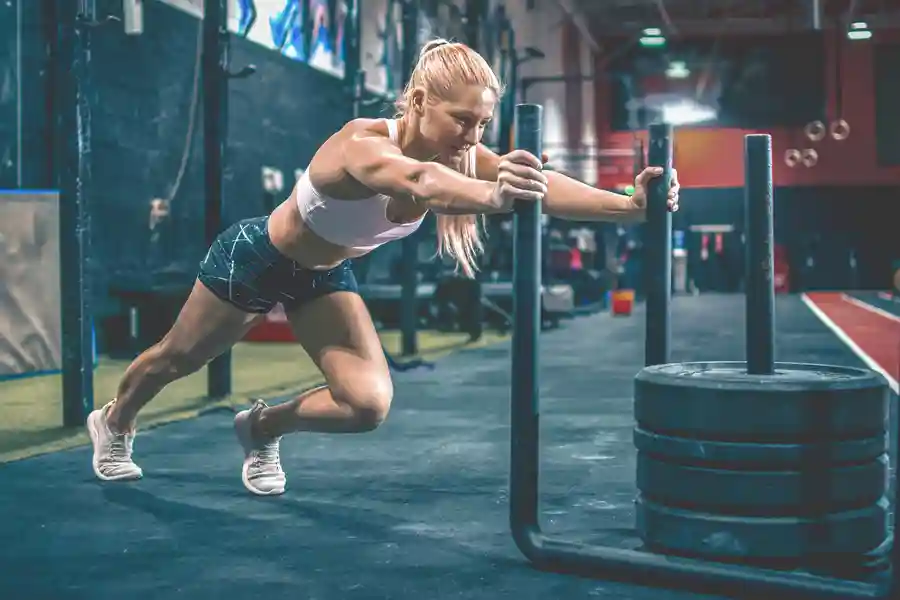 Female athlete performing sled push during HYROX fitness race