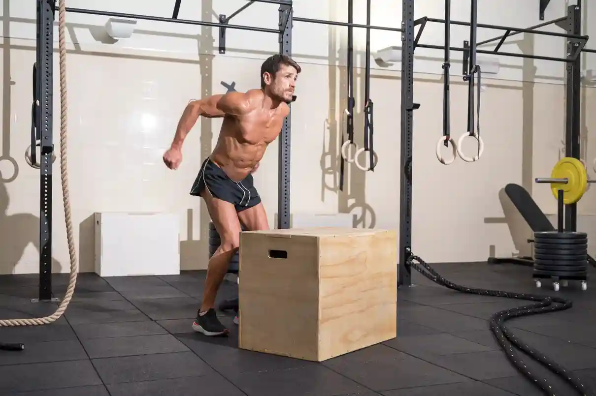 Male athlete performing a box jump, representing functional fitness training in HYROX vs DEKA Fit races