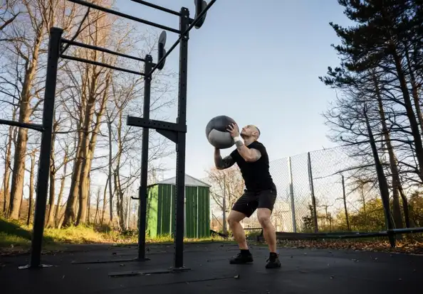 Male athlete performing wall balls during HYROX training, demonstrating endurance, pacing, and proper hip mobility for unbroken reps.