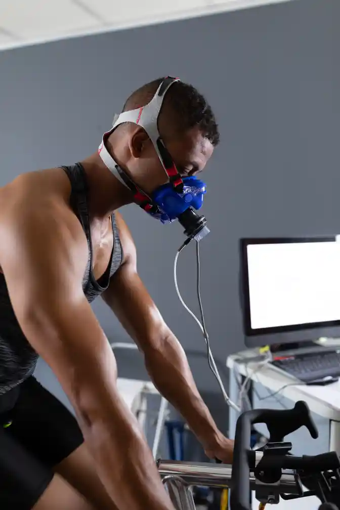 Man performing fitness test on stationary bike to evaluate endurance for hybrid athlete periodization