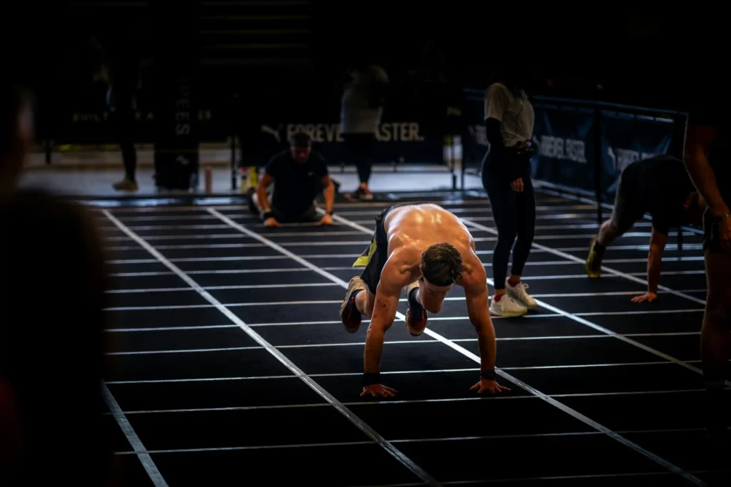 Male athlete performing burpee broad jumps during a HYROX race workout, focusing on power and endurance.