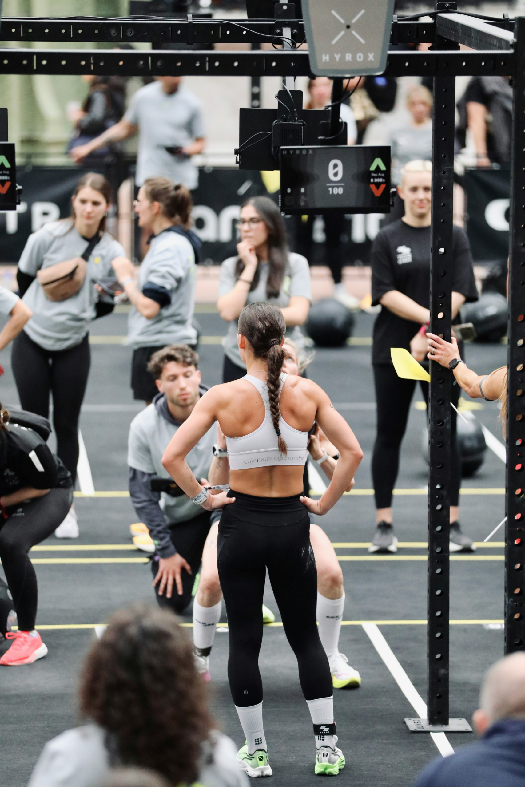 Female athlete applying HYROX training methodology during wall ball station at competition